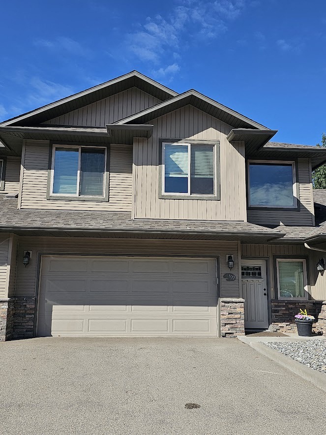 A house with a grey garage door and a brown roof.